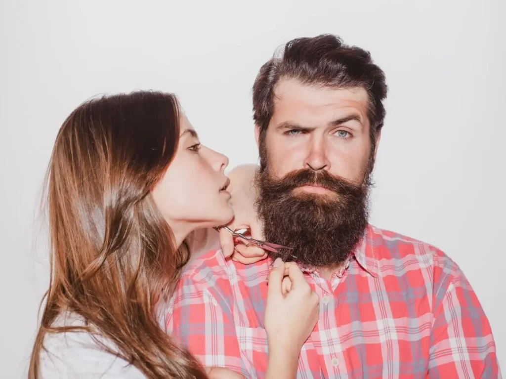Жінка підстригає чоловіку бороду