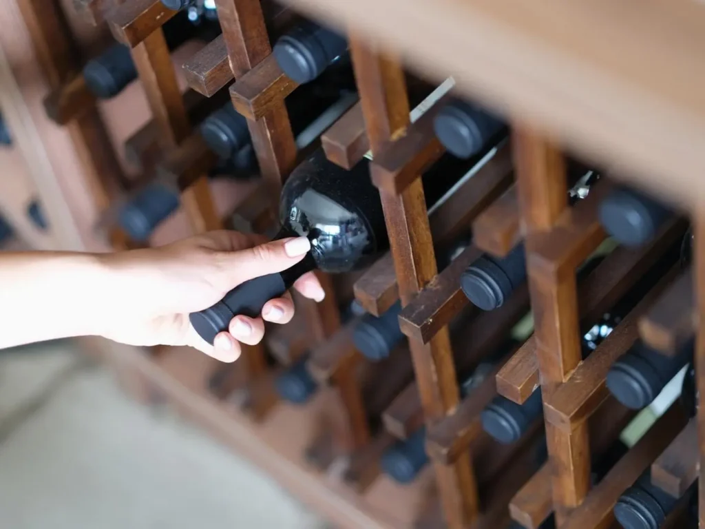 Жінка дістає вино з полиці